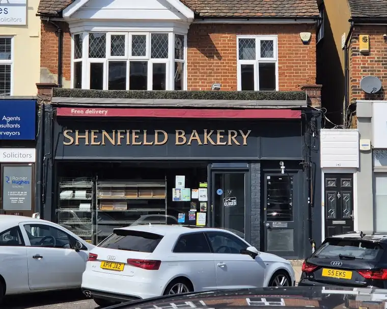 The Shenfield Bakery shopfront on Hutton Road: slate fascia with gold letters and a red striped awning